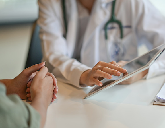 A consultant radiologist discussing diagnostic imaging options with a patient using a tablet.